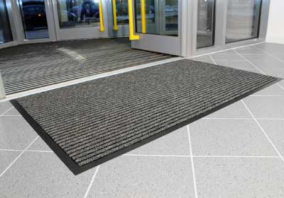 Close-up of non-slip rubber floor mat in a busy UK commercial entrance, highlighting texture and durability